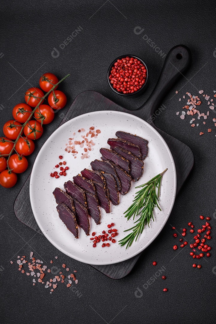 Deliciosa carne seca defumada ou carne seca de cavalo com especiarias e sal sobre um fundo escuro de concreto