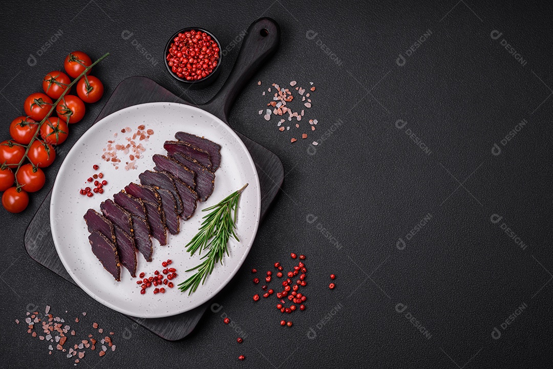 Deliciosa carne seca defumada ou carne seca de cavalo com especiarias e sal sobre um fundo escuro de concreto