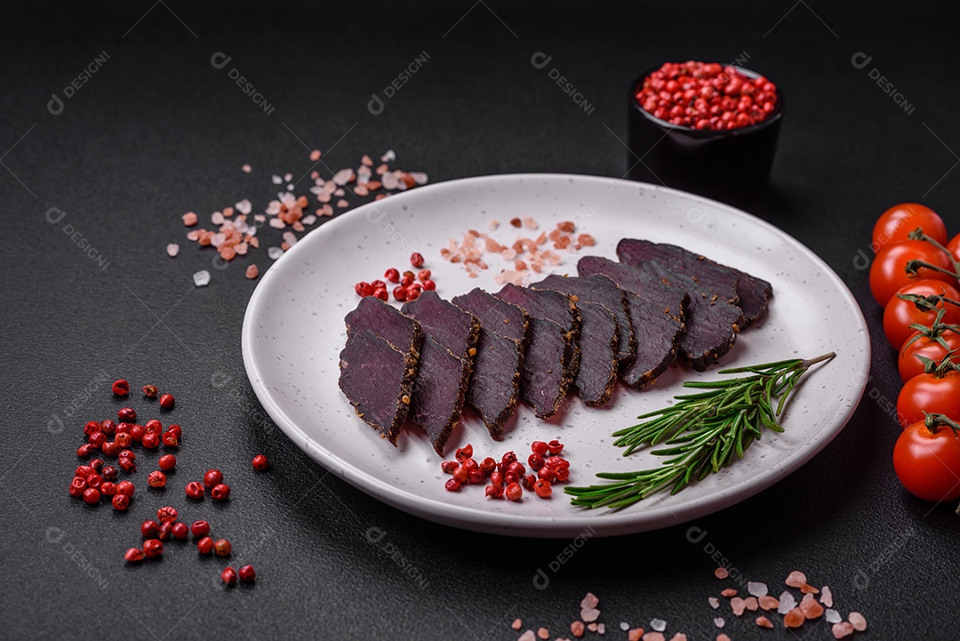 Deliciosa carne seca defumada ou carne seca de cavalo com especiarias e sal sobre um fundo escuro de concreto