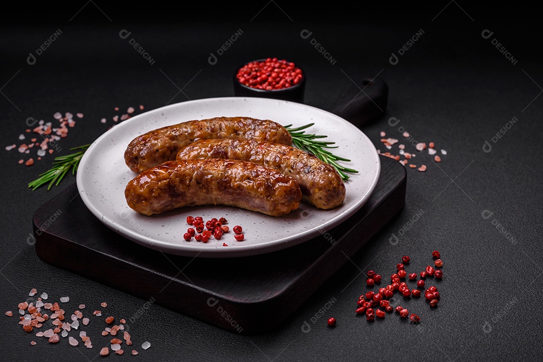 Deliciosas salsichas grelhadas fritas com sal, especiarias e ervas sobre um fundo escuro de concreto