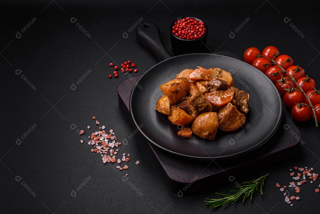 Delicioso ensopado fresco cozido com carne de porco ou carne bovina com batatas, cenouras, especiarias e ervas sobre um fundo escuro de concreto