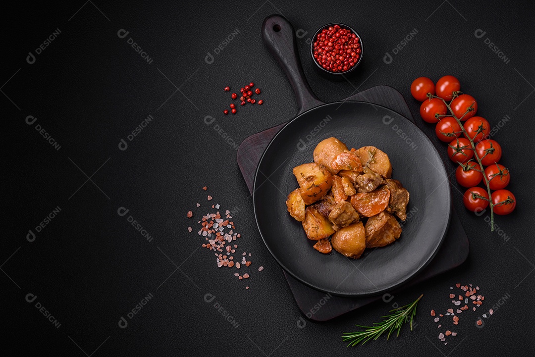 Delicioso ensopado fresco cozido com carne de porco ou carne bovina com batatas, cenouras, especiarias e ervas sobre um fundo escuro de concreto