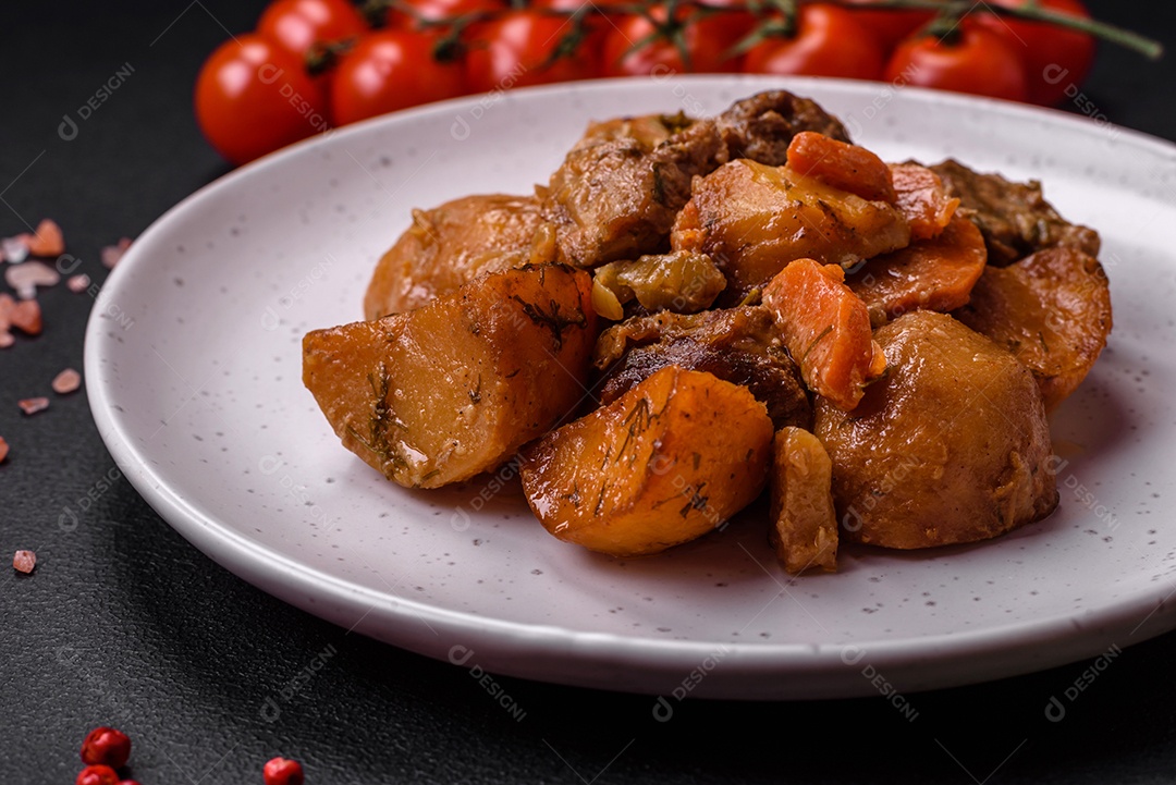Delicioso ensopado fresco cozido com carne de porco ou carne bovina com batatas, cenouras, especiarias e ervas sobre um fundo escuro de concreto
