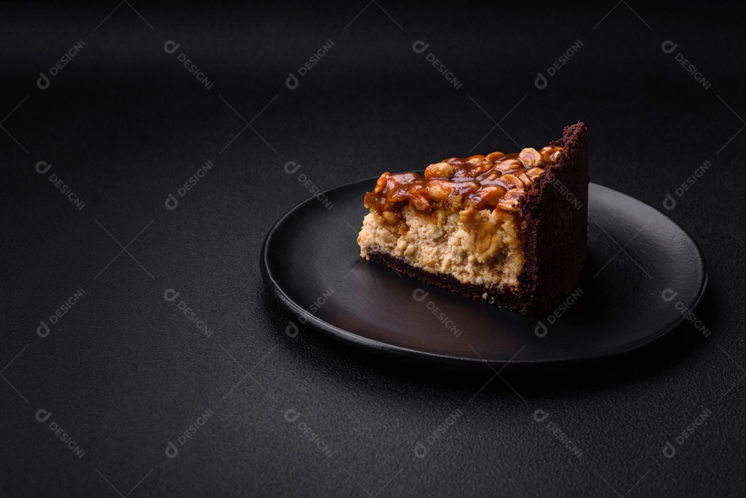 Delicioso bolo de queijo fresco ou snickers com creme e nozes em uma placa cerâmica sobre um fundo escuro de concreto