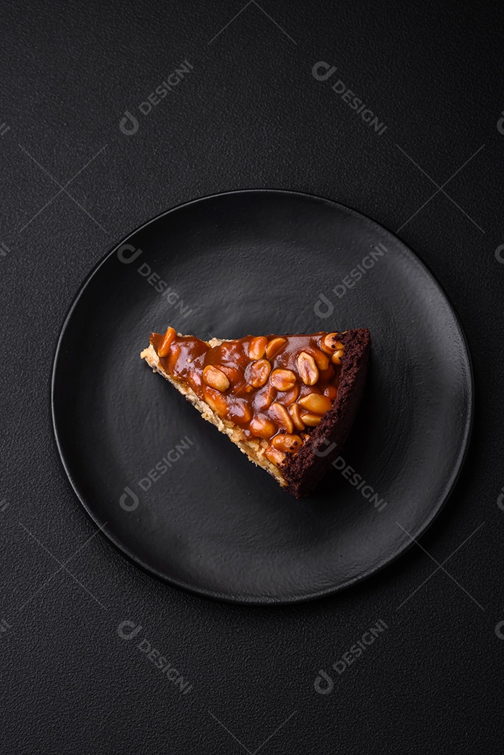 Delicioso bolo de queijo fresco ou snickers com creme e nozes em uma placa cerâmica sobre um fundo escuro de concreto