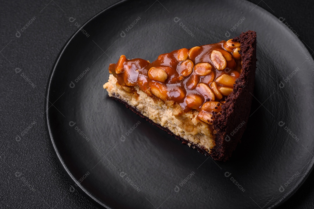 Delicioso bolo de queijo fresco ou snickers com creme e nozes em uma placa cerâmica sobre um fundo escuro de concreto