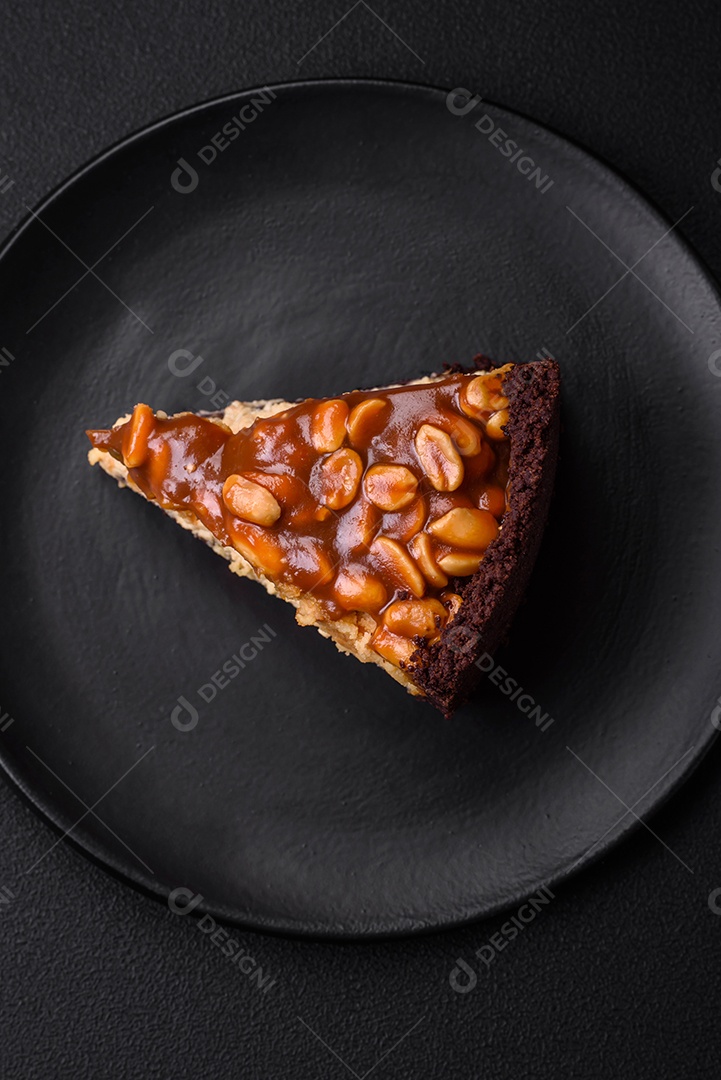 Delicioso bolo de queijo fresco ou snickers com creme e nozes em uma placa cerâmica sobre um fundo escuro de concreto