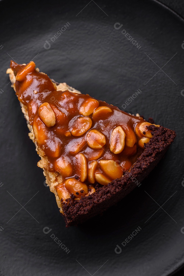 Delicioso bolo de queijo fresco ou snickers com creme e nozes em uma placa cerâmica sobre um fundo escuro de concreto