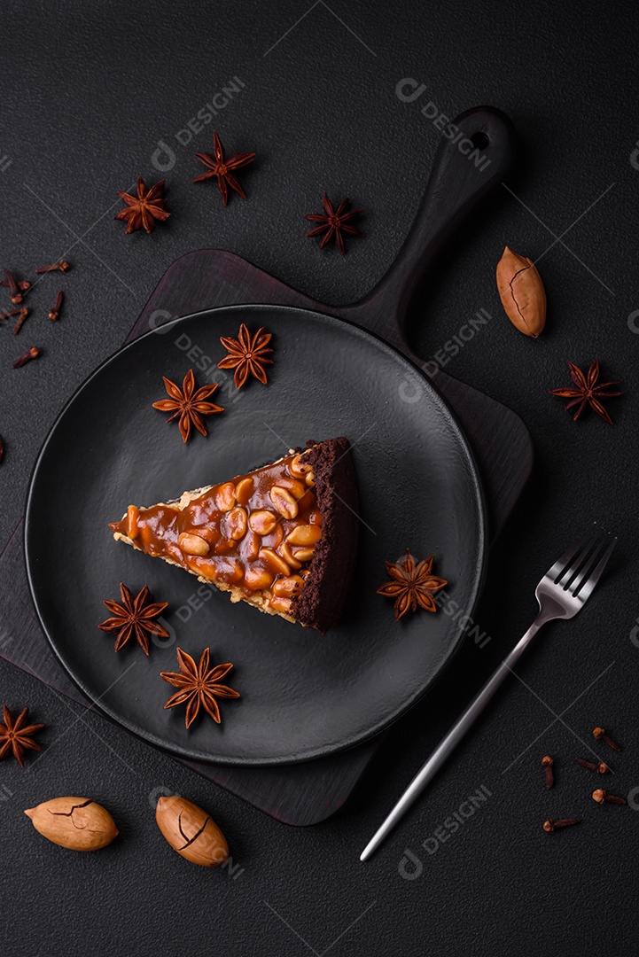 Delicioso bolo de queijo fresco ou snickers com creme e nozes em uma placa cerâmica sobre um fundo escuro de concreto