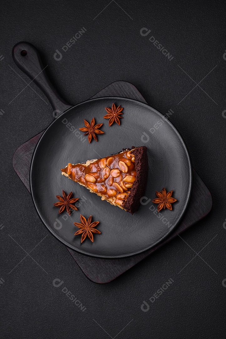 Delicioso bolo de queijo fresco ou snickers com creme e nozes em uma placa cerâmica sobre um fundo escuro de concreto