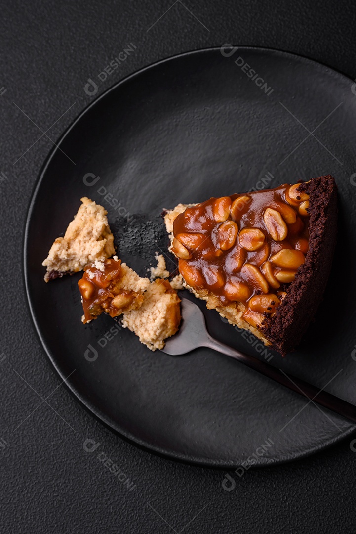 Delicioso bolo de queijo fresco ou snickers com creme e nozes em uma placa cerâmica sobre um fundo escuro de concreto
