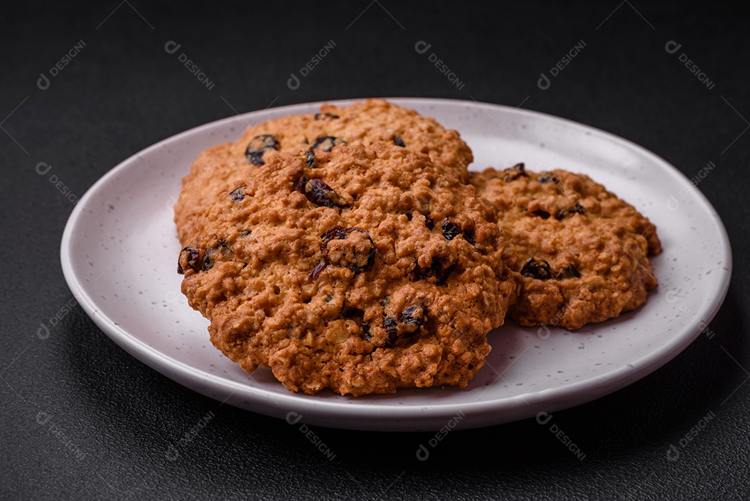 Deliciosos biscoitos de aveia assados ​​em um fundo escuro de concreto. Doces no café da manhã