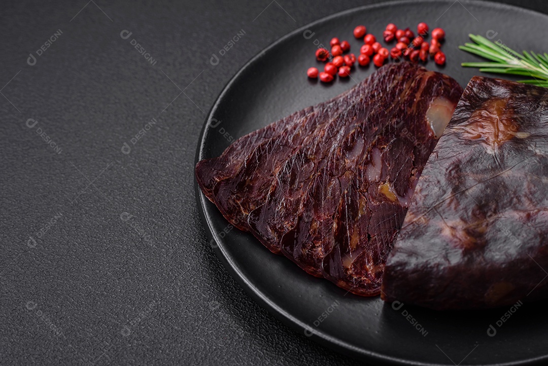Deliciosa salsicha de carne de cavalo mahan fumada ou curada com especiarias e ervas sobre um fundo escuro de concreto
