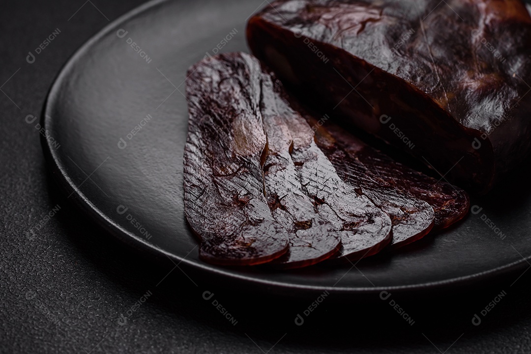 Deliciosa salsicha de carne de cavalo mahan fumada ou curada com especiarias e ervas sobre um fundo escuro de concreto
