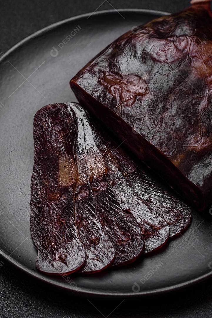 Deliciosa salsicha de carne de cavalo mahan fumada ou curada com especiarias e ervas sobre um fundo escuro de concreto