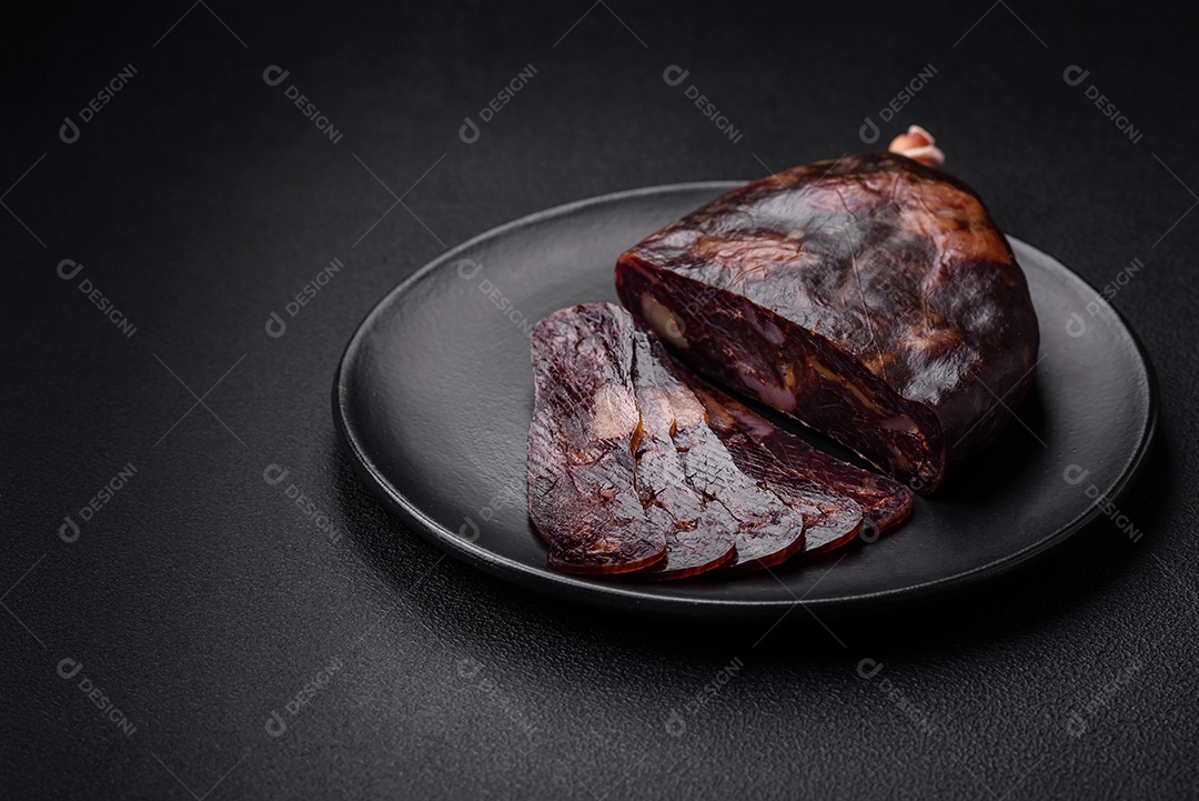 Deliciosa salsicha de carne de cavalo mahan fumada ou curada com especiarias e ervas sobre um fundo escuro de concreto