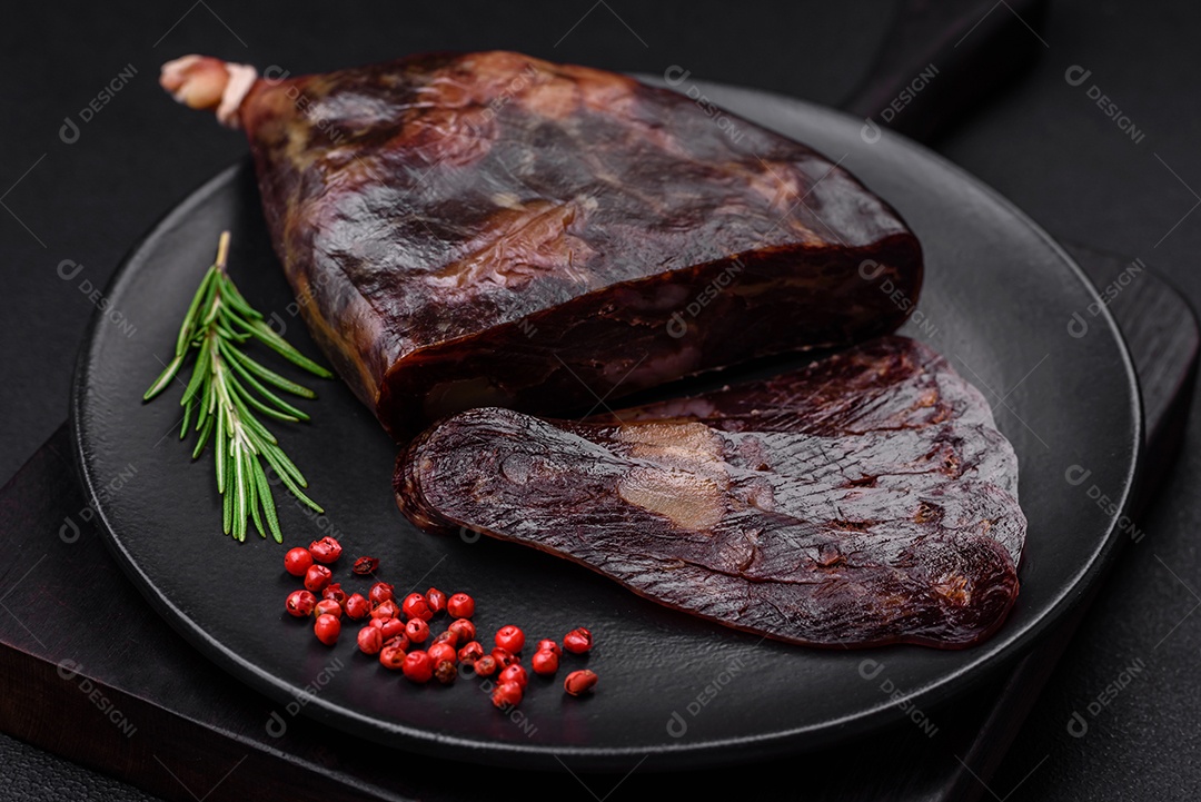Deliciosa salsicha de carne de cavalo mahan fumada ou curada com especiarias e ervas sobre um fundo escuro de concreto