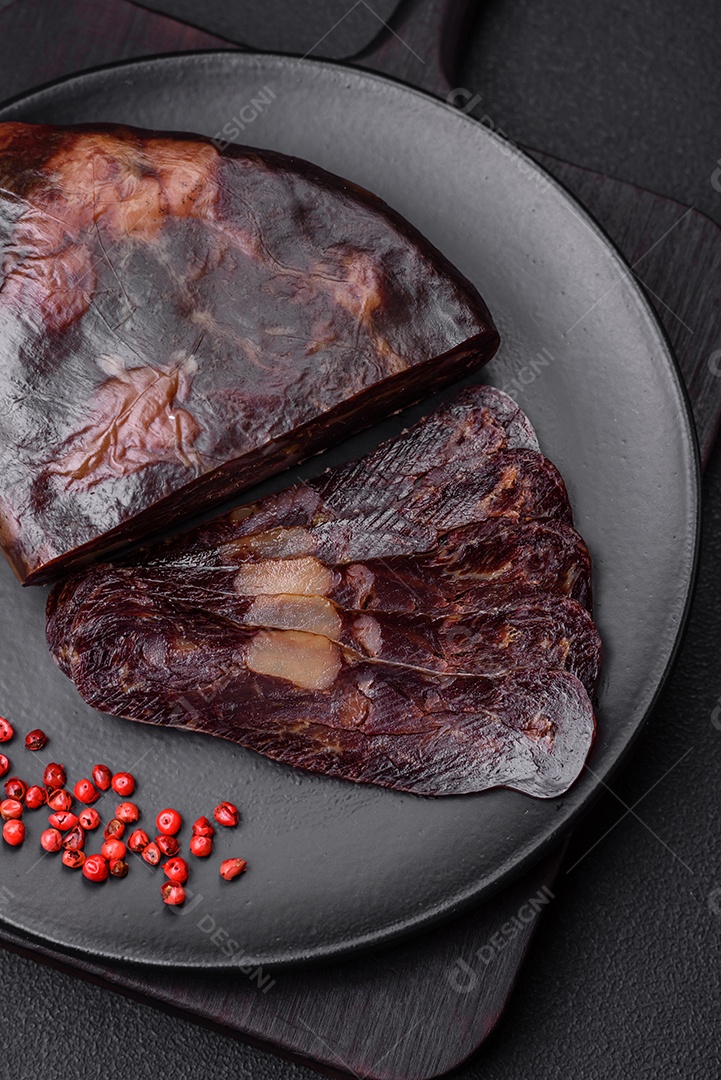 Deliciosa salsicha de carne de cavalo mahan fumada ou curada com especiarias e ervas sobre um fundo escuro de concreto