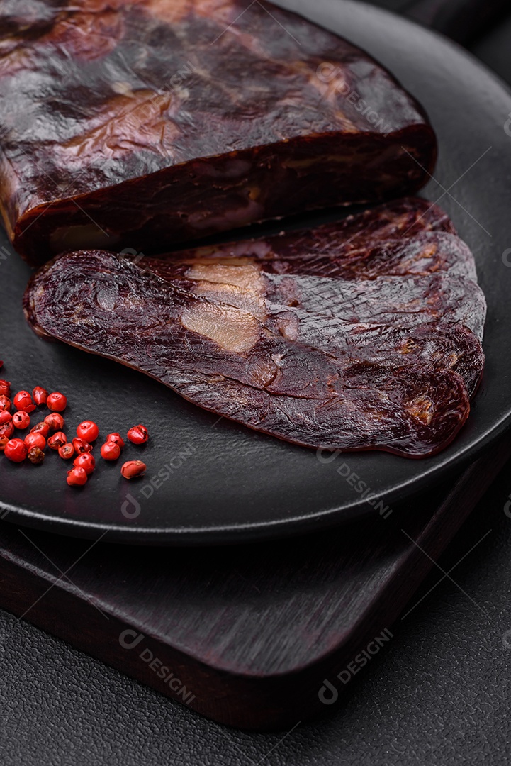 Deliciosa salsicha de carne de cavalo mahan fumada ou curada com especiarias e ervas sobre um fundo escuro de concreto