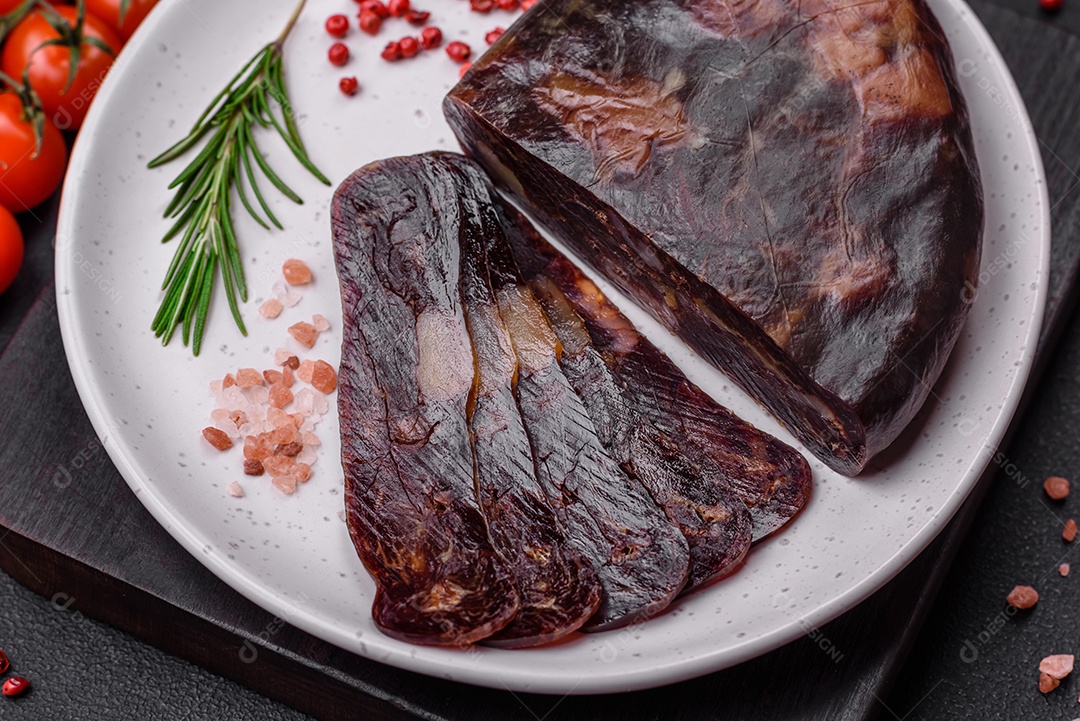 Deliciosa salsicha de carne de cavalo mahan fumada ou curada com especiarias e ervas sobre um fundo escuro de concreto