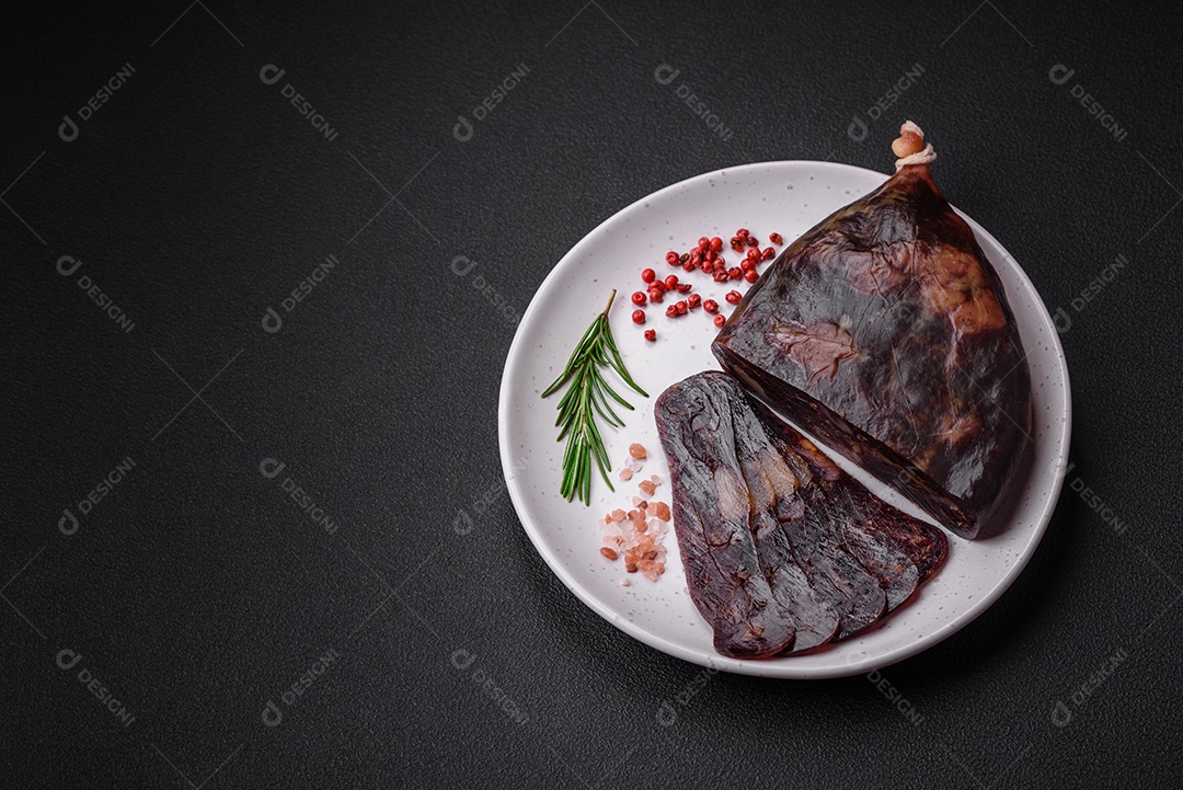 Deliciosa salsicha de carne de cavalo mahan fumada ou curada com especiarias e ervas sobre um fundo escuro de concreto