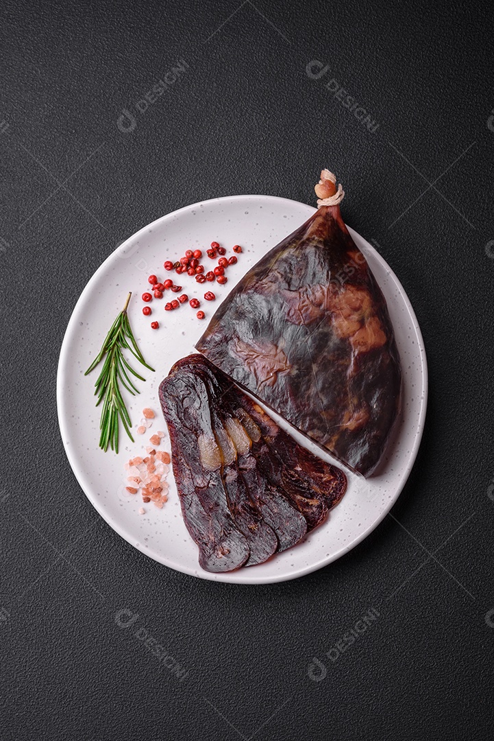 Deliciosa salsicha de carne de cavalo mahan fumada ou curada com especiarias e ervas sobre um fundo escuro de concreto