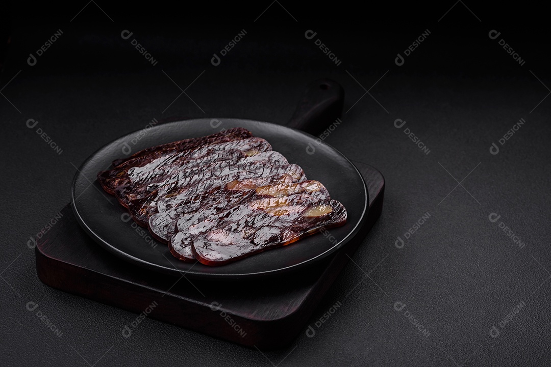 Deliciosa salsicha de carne de cavalo mahan fumada ou curada com especiarias e ervas sobre um fundo escuro de concreto