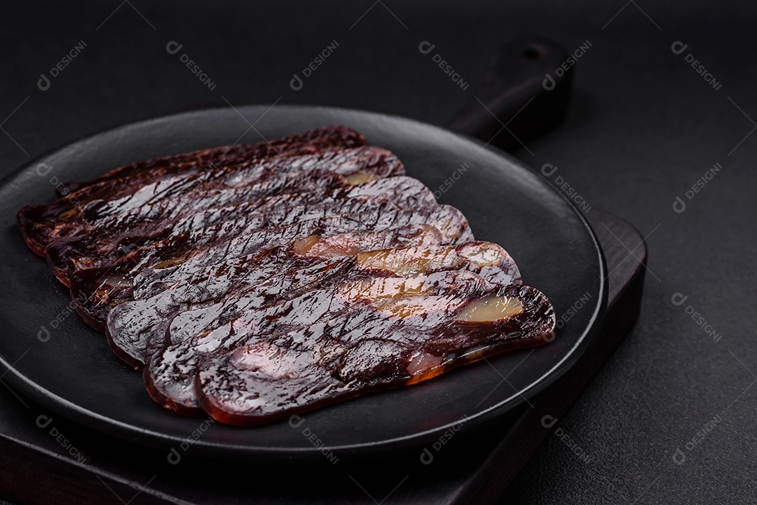 Deliciosa salsicha de carne de cavalo mahan fumada ou curada com especiarias e ervas sobre um fundo escuro de concreto