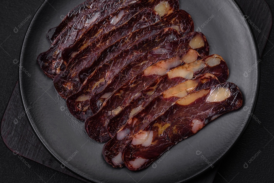 Deliciosa salsicha de carne de cavalo mahan fumada ou curada com especiarias e ervas sobre um fundo escuro de concreto