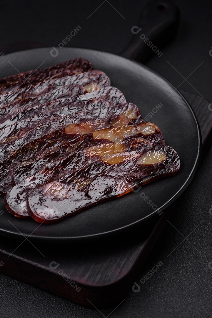 Deliciosa salsicha de carne de cavalo mahan fumada ou curada com especiarias e ervas sobre um fundo escuro de concreto