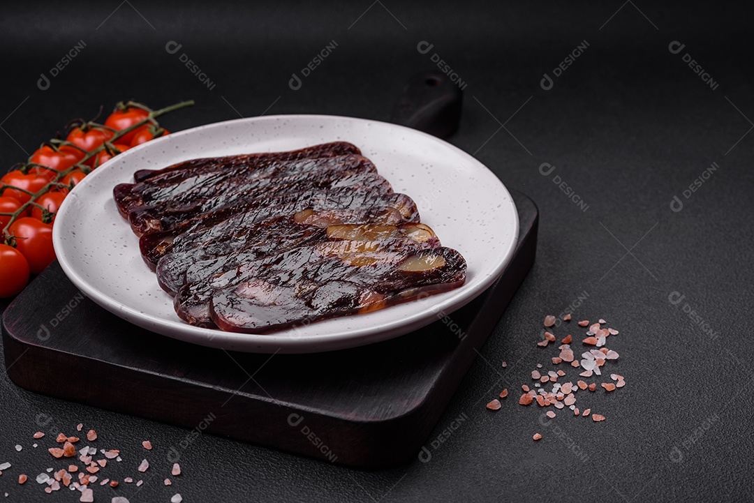 Deliciosa salsicha de carne de cavalo mahan fumada ou curada com especiarias e ervas sobre um fundo escuro de concreto