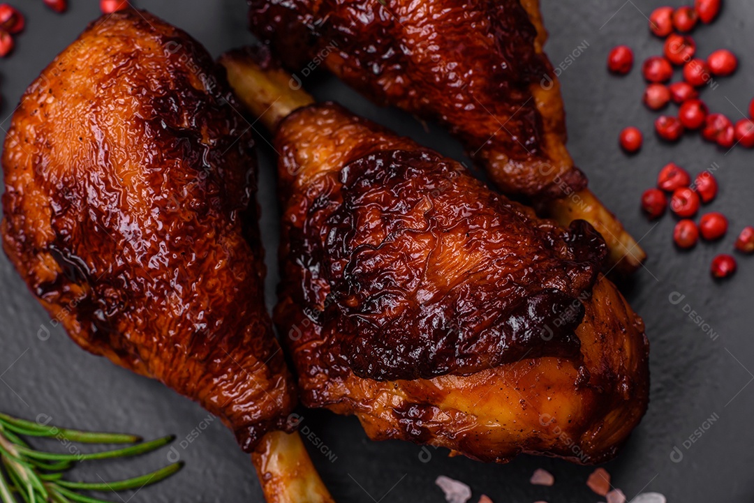 Deliciosas pernas de frango grelhado com especiarias e ervas em molho teriyaki sobre um fundo escuro de concreto