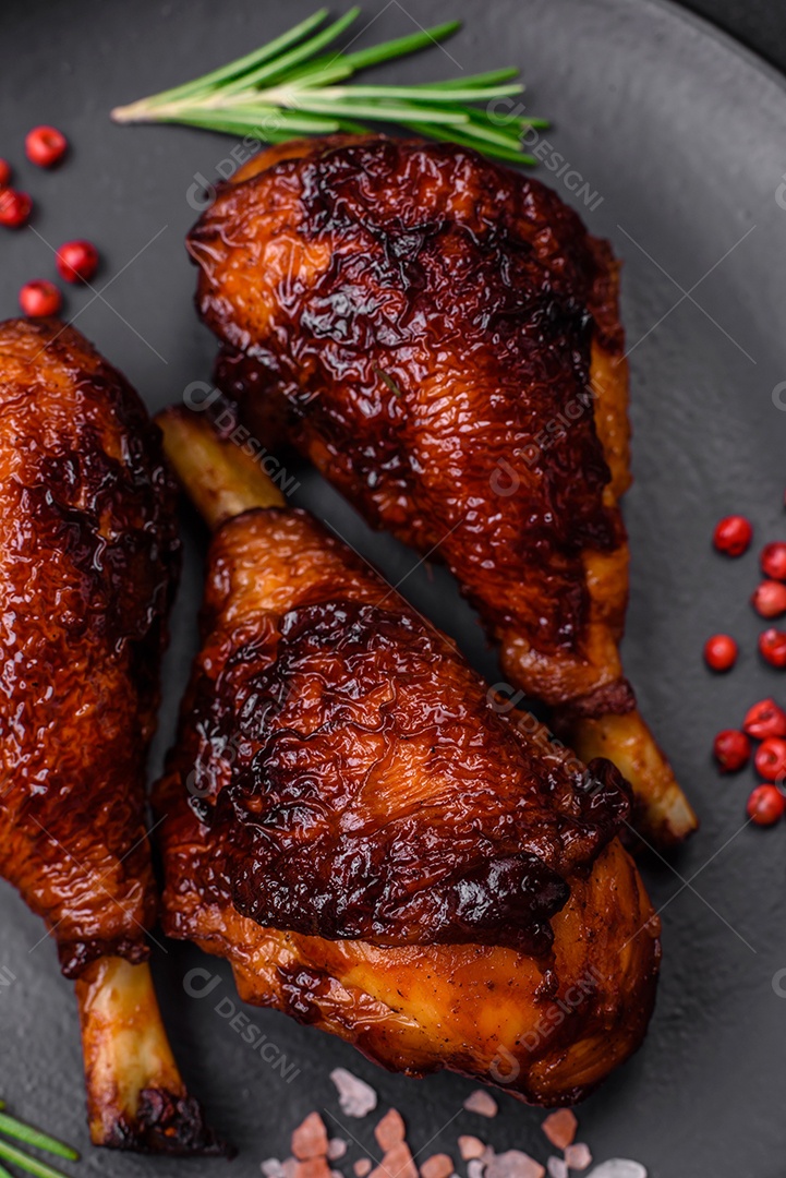 Deliciosas pernas de frango grelhado com especiarias e ervas em molho teriyaki sobre um fundo escuro de concreto