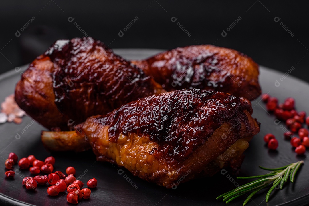 Deliciosas pernas de frango grelhado com especiarias e ervas em molho teriyaki sobre um fundo escuro de concreto