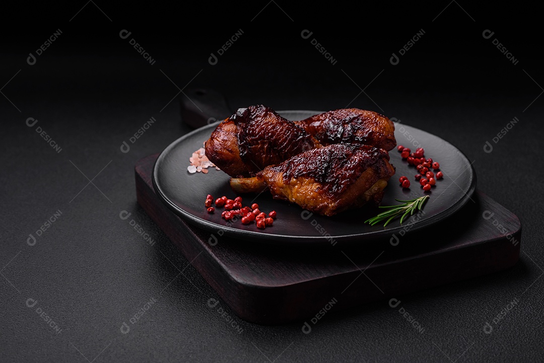 Deliciosas pernas de frango grelhado com especiarias e ervas em molho teriyaki sobre um fundo escuro de concreto