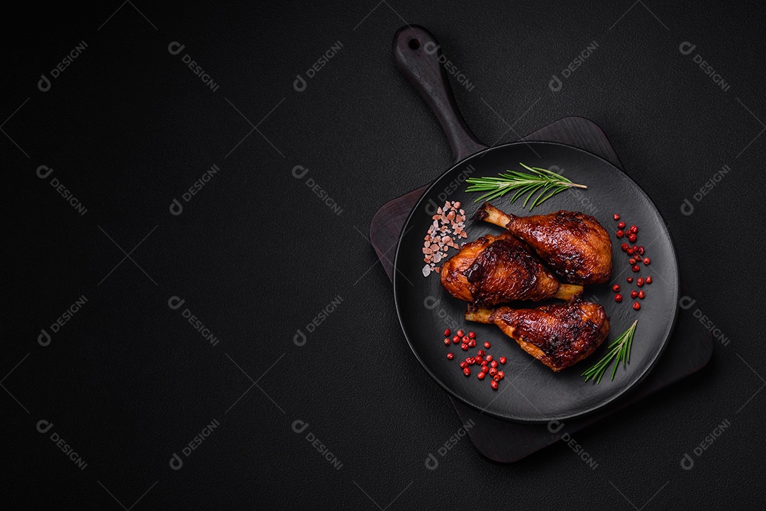 Deliciosas pernas de frango grelhado com especiarias e ervas em molho teriyaki sobre um fundo escuro de concreto