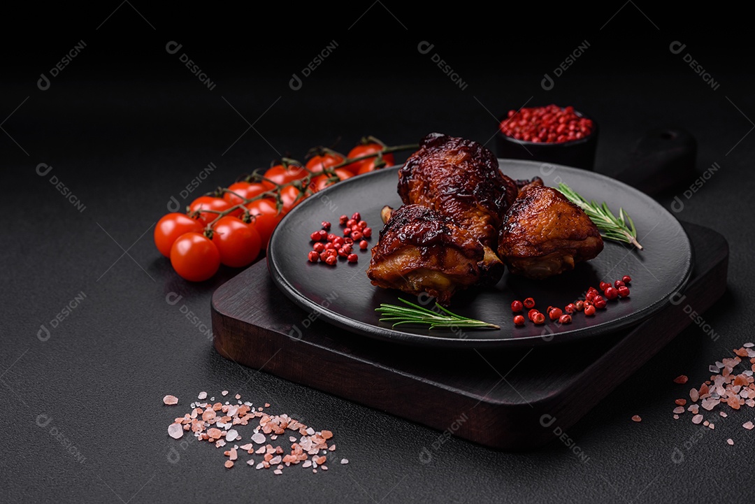 Deliciosas pernas de frango grelhado com especiarias e ervas em molho teriyaki sobre um fundo escuro de concreto