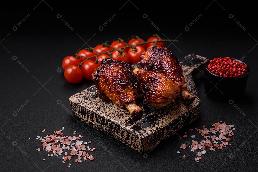 Deliciosas pernas de frango grelhado com especiarias e ervas em molho teriyaki sobre um fundo escuro de concreto