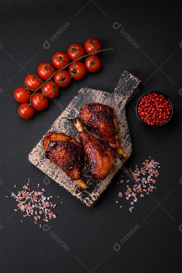 Deliciosas pernas de frango grelhado com especiarias e ervas em molho teriyaki sobre um fundo escuro de concreto