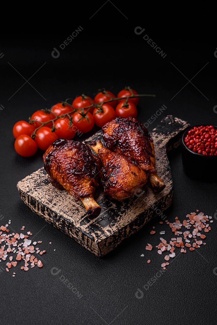 Deliciosas pernas de frango grelhado com especiarias e ervas em molho teriyaki sobre um fundo escuro de concreto