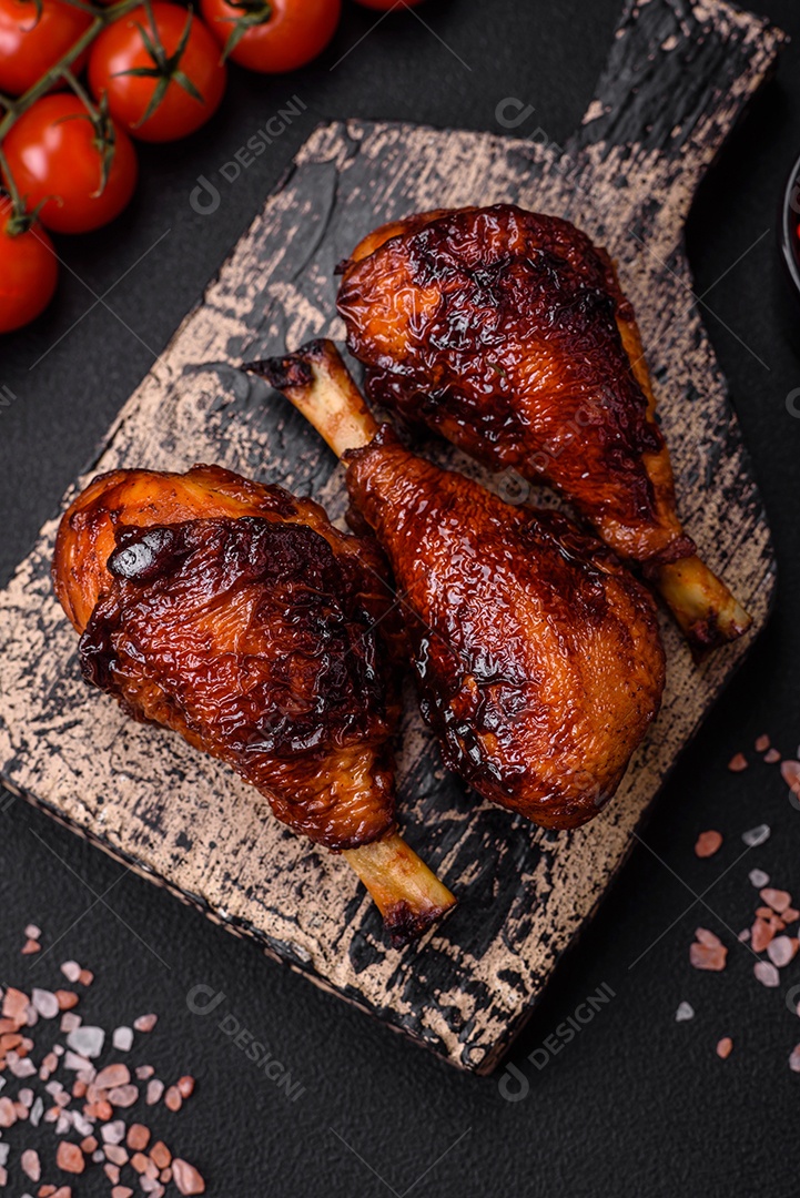 Deliciosas pernas de frango grelhado com especiarias e ervas em molho teriyaki sobre um fundo escuro de concreto