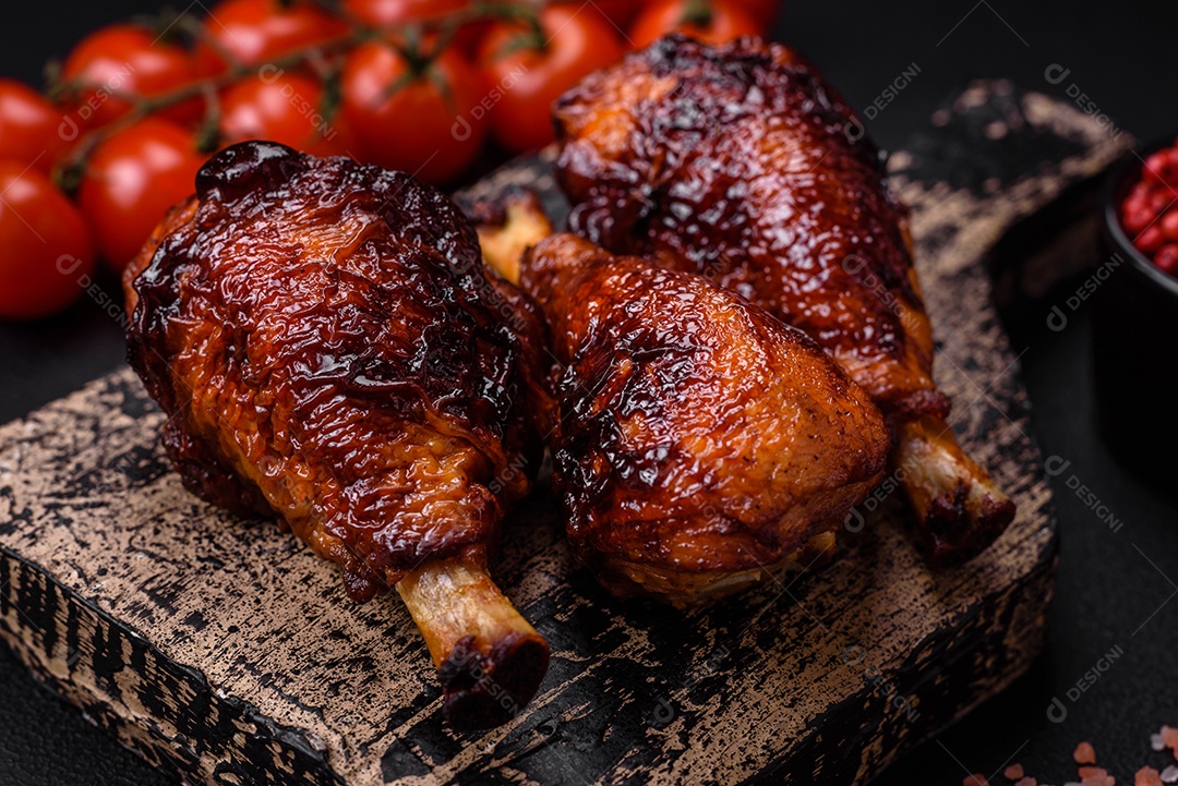 Deliciosas pernas de frango grelhado com especiarias e ervas em molho teriyaki sobre um fundo escuro de concreto