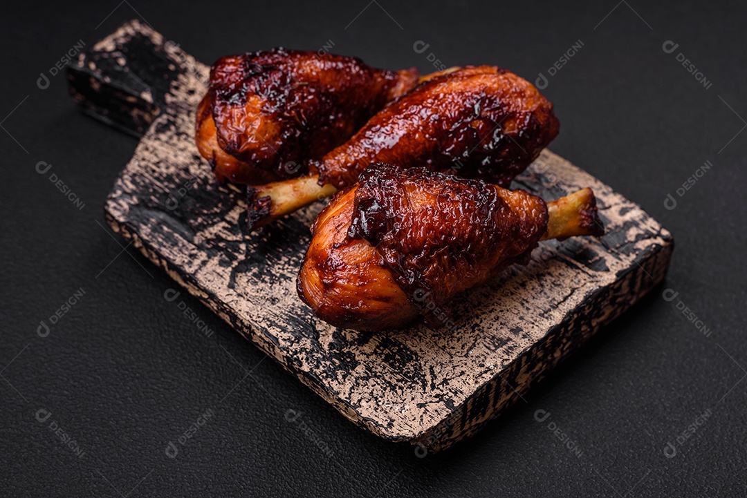 Deliciosas pernas de frango grelhado com especiarias e ervas em molho teriyaki sobre um fundo escuro de concreto