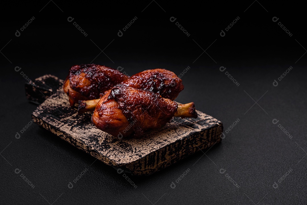 Deliciosas pernas de frango grelhado com especiarias e ervas em molho teriyaki sobre um fundo escuro de concreto