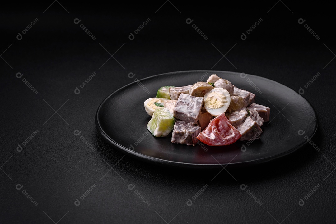 Deliciosa salada com língua de boi cozida, ovos de codorna, tomate e pepino sobre um fundo escuro de concreto