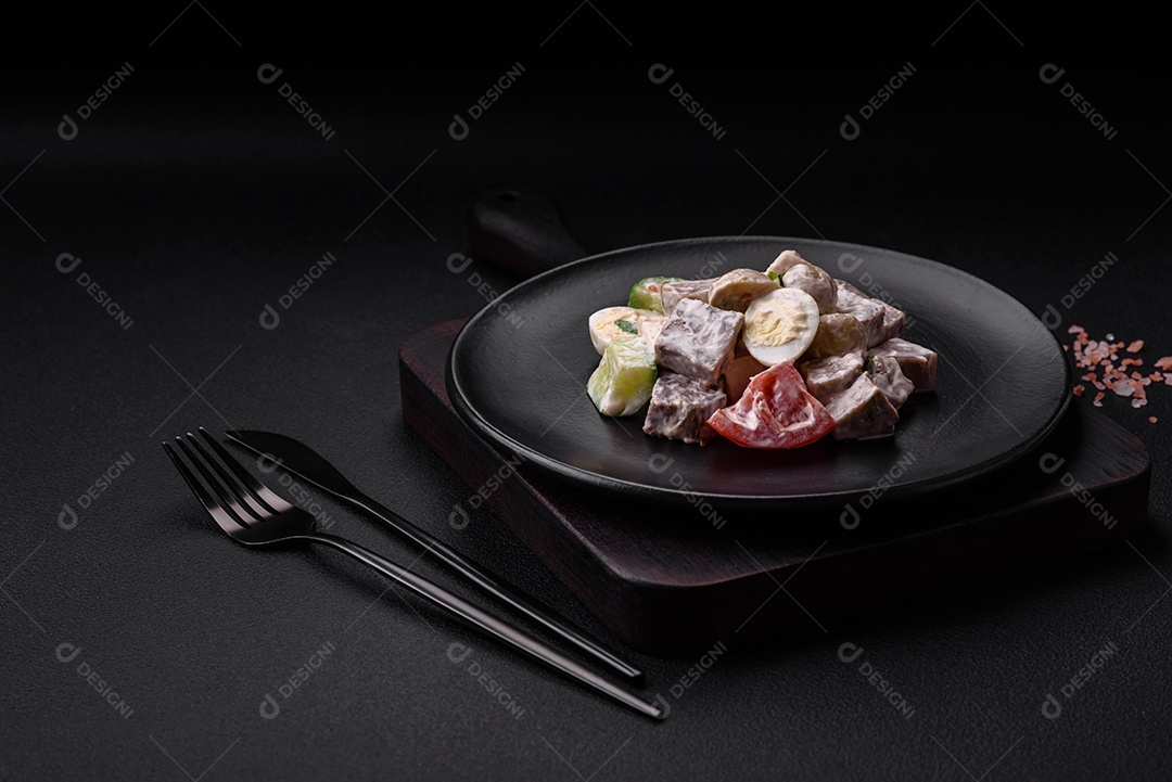 Deliciosa salada com língua de boi cozida, ovos de codorna, tomate e pepino sobre um fundo escuro de concreto