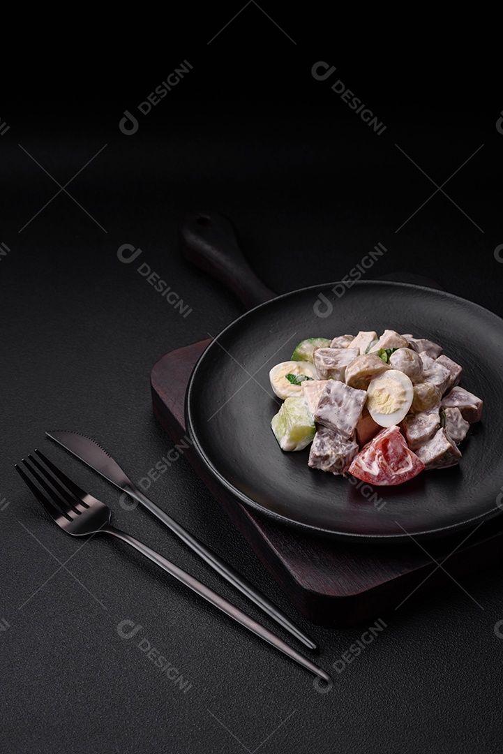 Deliciosa salada com língua de boi cozida, ovos de codorna, tomate e pepino sobre um fundo escuro de concreto