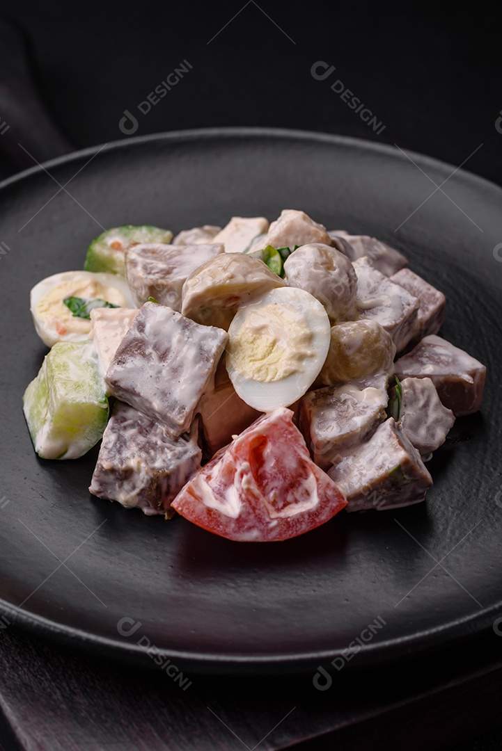 Deliciosa salada com língua de boi cozida, ovos de codorna, tomate e pepino sobre um fundo escuro de concreto