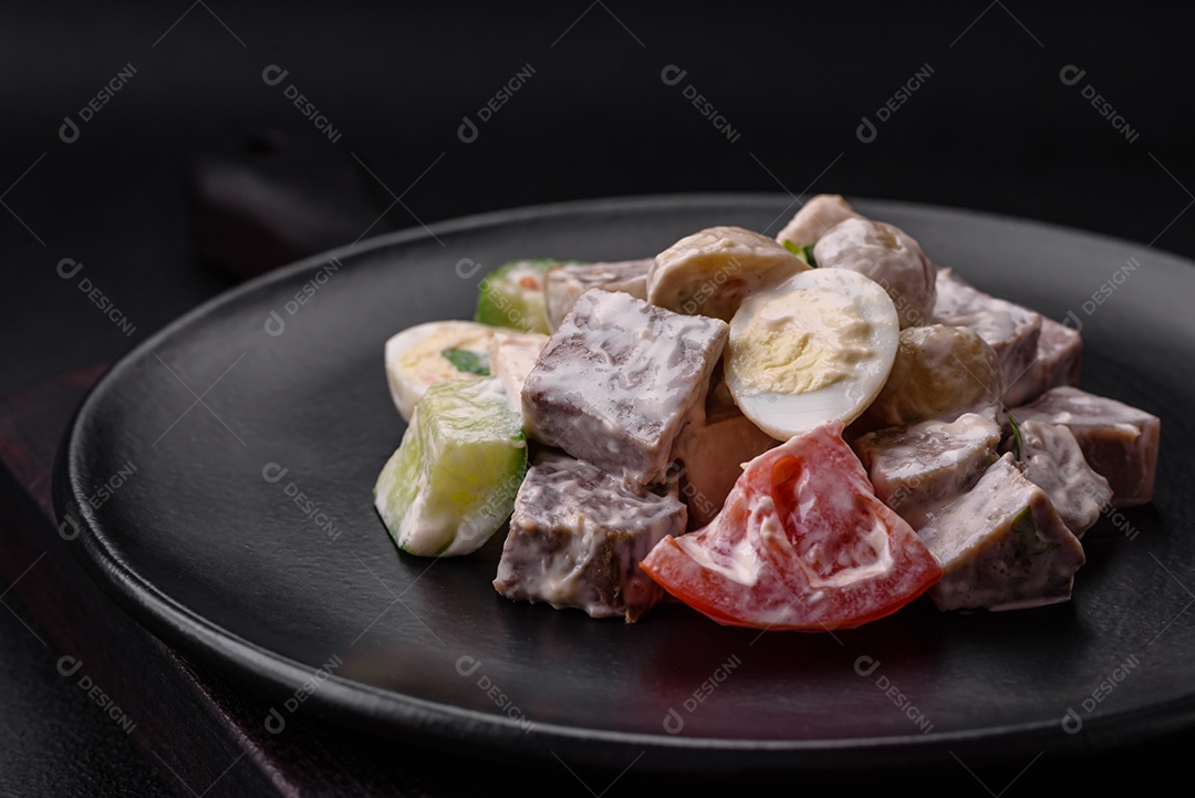 Deliciosa salada com língua de boi cozida, ovos de codorna, tomate e pepino sobre um fundo escuro de concreto