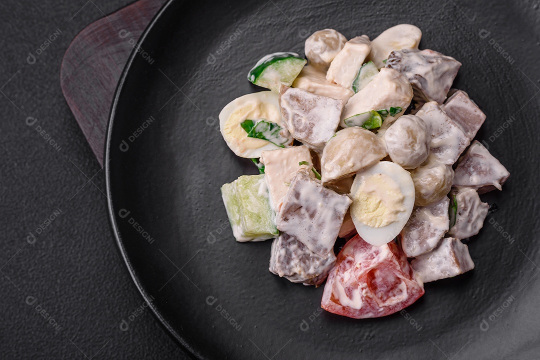 Deliciosa salada com língua de boi cozida, ovos de codorna, tomate e pepino sobre um fundo escuro de concreto
